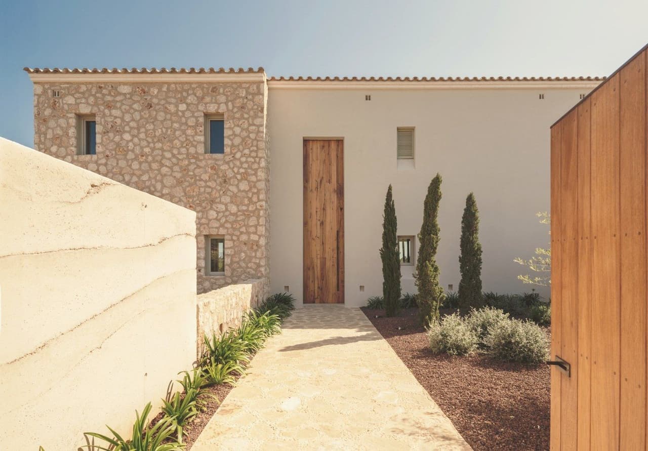 Eingang einer mallorquinischen Finca mit handgesetztem Naturstein, massiver Holzt?r und Zypressen - Fuster & Fuster Construcciones