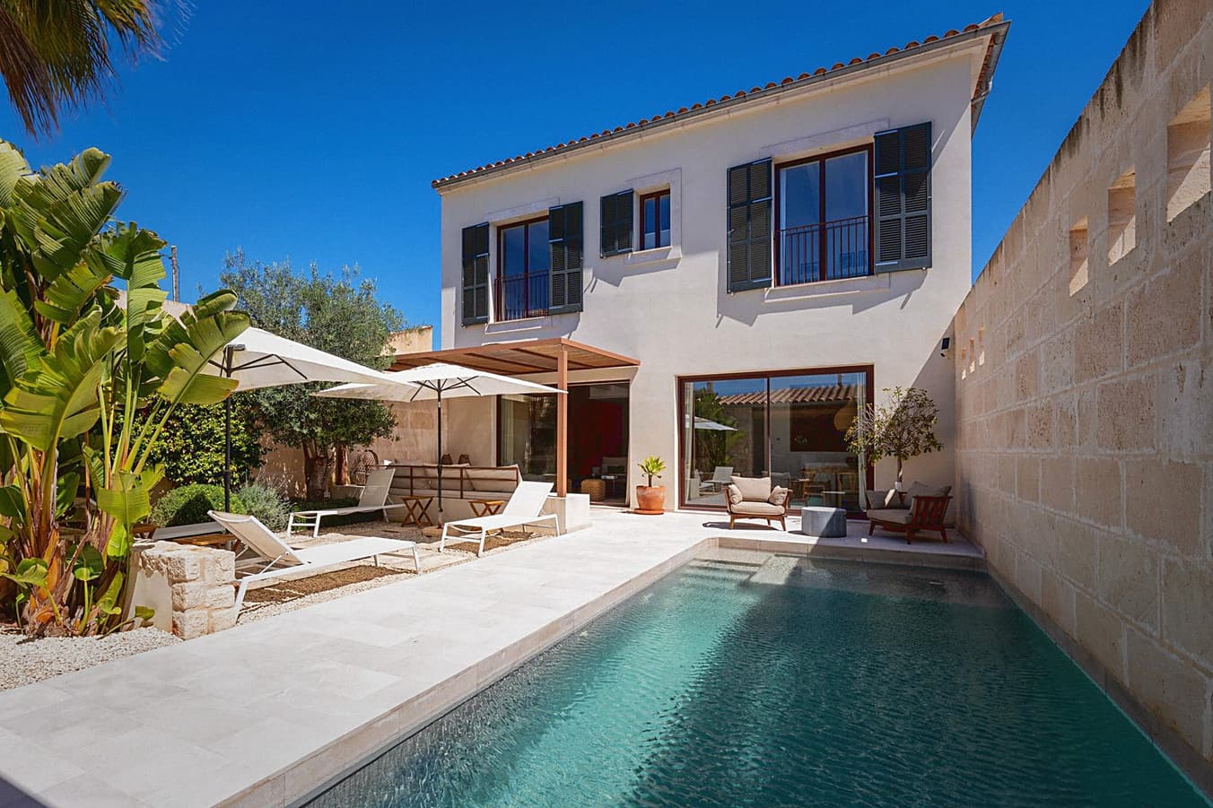 Pool mit Holzpergola und Fassade mit Holzlamellen-Fensterläden